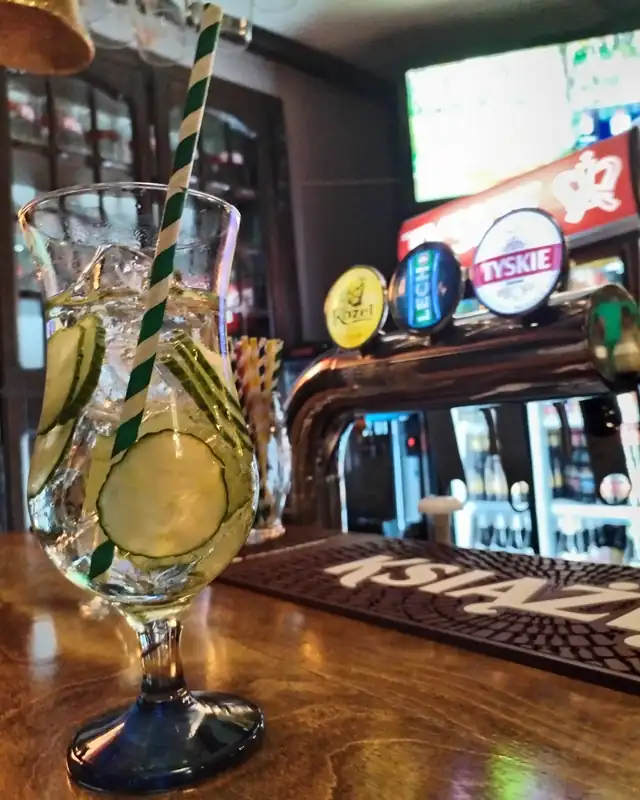 Drink z plastrami ogórka i słomką w kielichu na barze