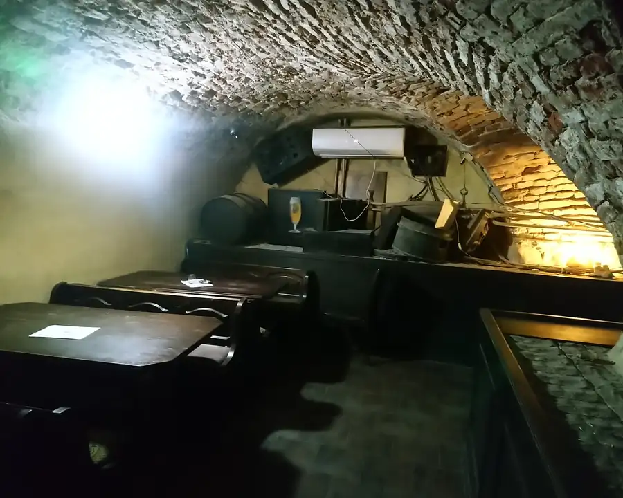 Sala pod ceglanym sklepieniem ze stołami i kanapami